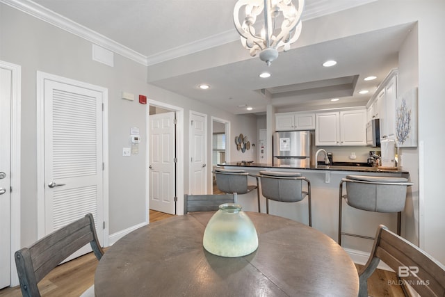 dining area featuring crown molding, baseboards, a tray ceiling, recessed lighting, and light wood-style floors