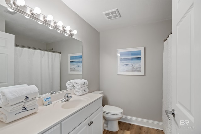 full bathroom with visible vents, toilet, wood finished floors, baseboards, and vanity