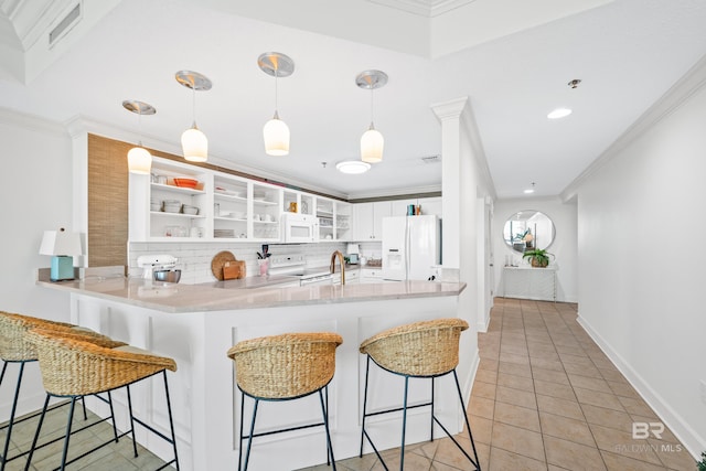 kitchen featuring white cabinets, a breakfast bar, white appliances, and kitchen peninsula