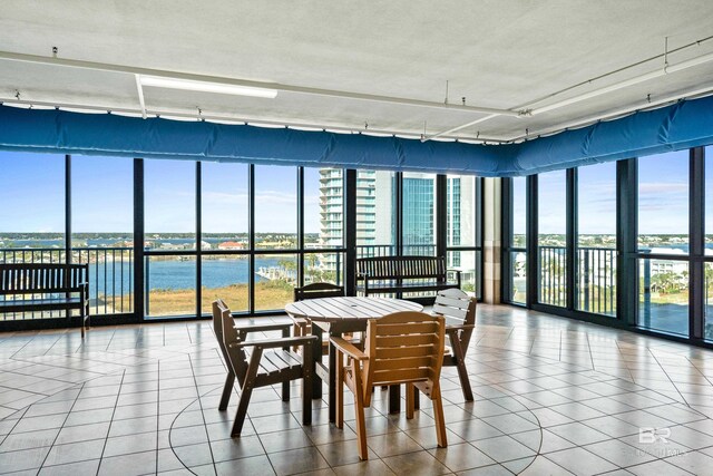 dining space with a textured ceiling, a water view, tile patterned floors, and a healthy amount of sunlight