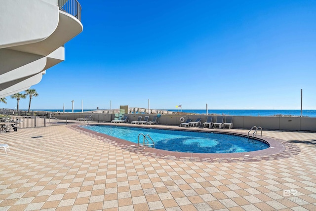 view of pool featuring a patio area and a water view