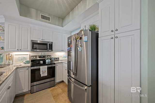 kitchen with light stone countertops, white cabinetry, appliances with stainless steel finishes, and tasteful backsplash