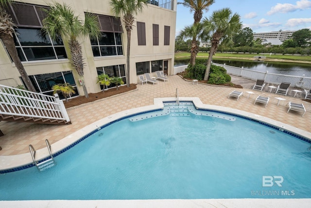 view of pool with a water view and a patio