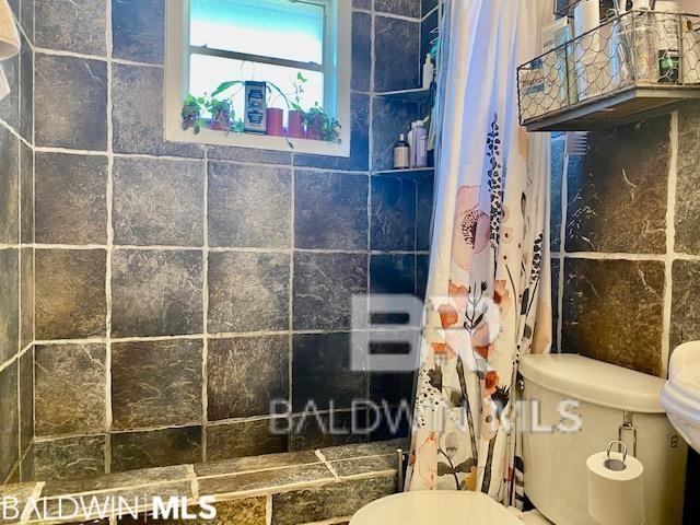 bathroom featuring tile walls, a shower with shower curtain, and toilet