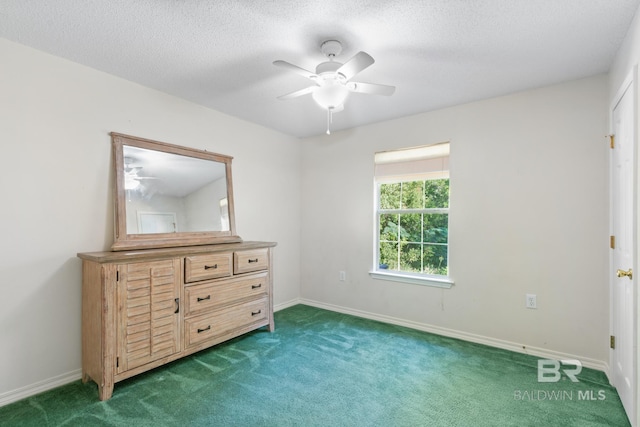 unfurnished bedroom featuring ceiling fan, a textured ceiling, and dark carpet