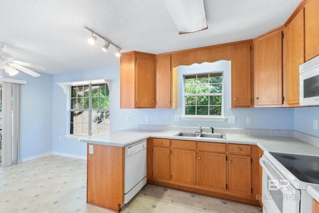 kitchen featuring white appliances, kitchen peninsula, sink, and a wealth of natural light