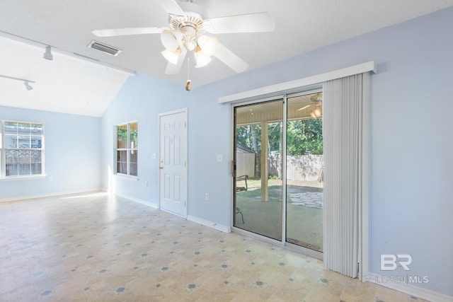 spare room featuring rail lighting, lofted ceiling, ceiling fan, and a wealth of natural light