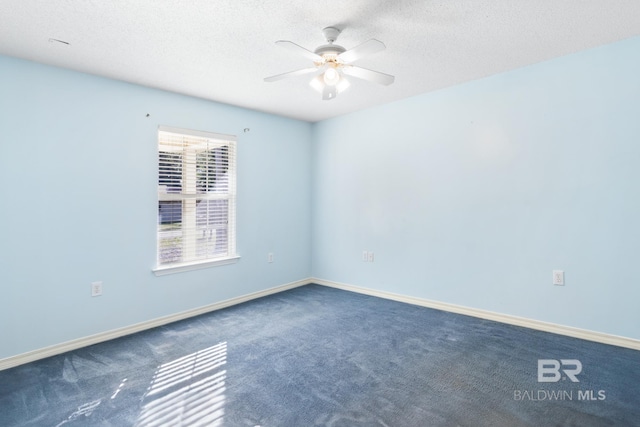 empty room with dark colored carpet, ceiling fan, and a textured ceiling