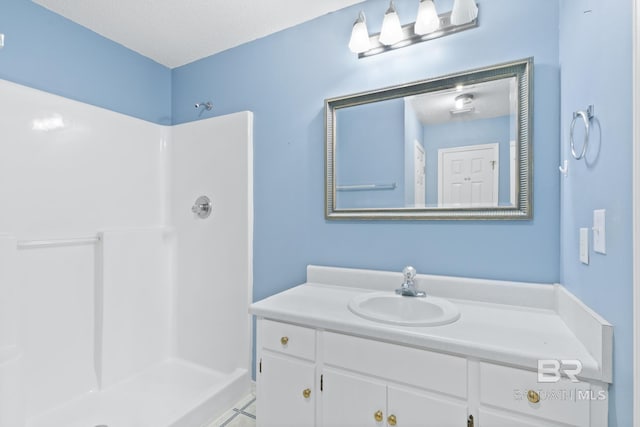 bathroom featuring walk in shower, vanity, a textured ceiling, and tile patterned floors