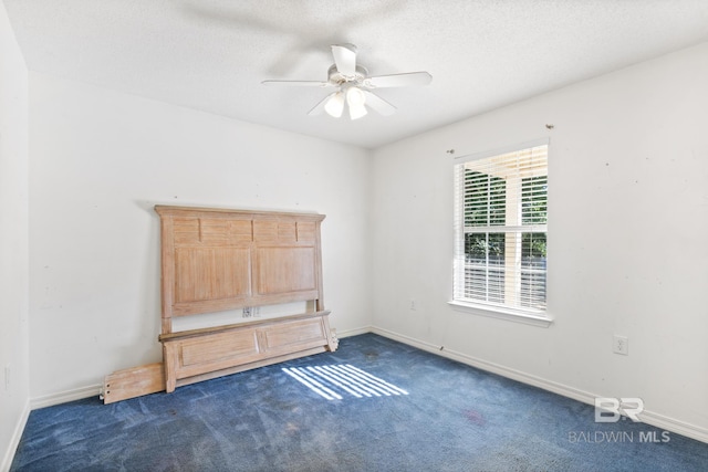 carpeted empty room featuring ceiling fan and a textured ceiling