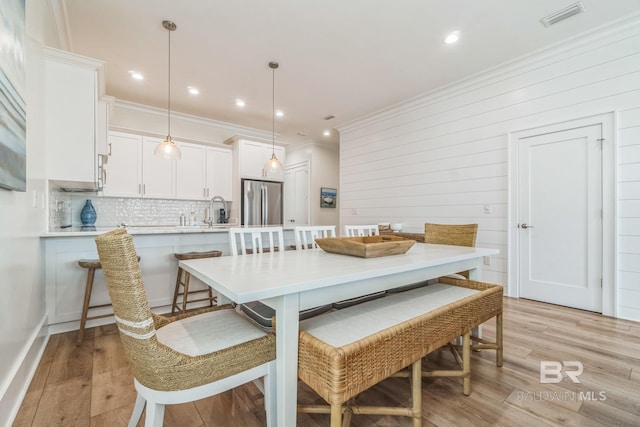 1050 W Beach Blvd Unit E, Gulf Shores, AL 36542 - dining area featuring ornamental molding, light wood-style floors, recessed lighting, and wood walls