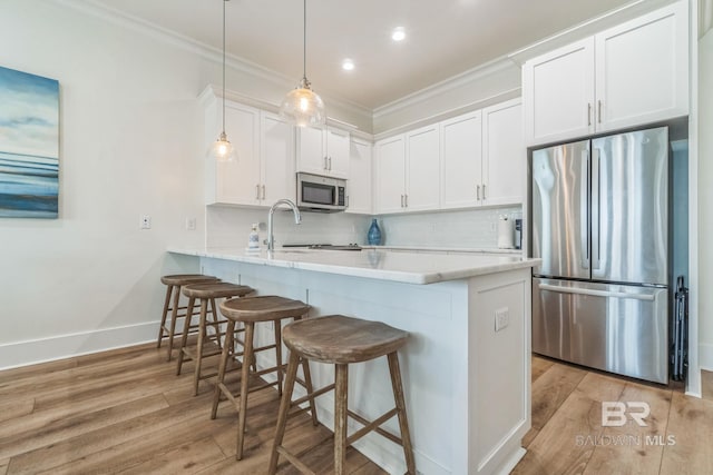 1050 W Beach Blvd Unit E, Gulf Shores, AL 36542 - kitchen featuring appliances with stainless steel finishes, crown molding, light wood finished floors, a peninsula, and white cabinets
