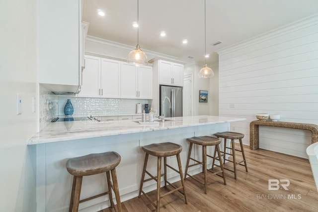 1050 W Beach Blvd Unit E, Gulf Shores, AL 36542 - kitchen with a peninsula, white cabinetry, crown molding, tasteful backsplash, and light stone counters