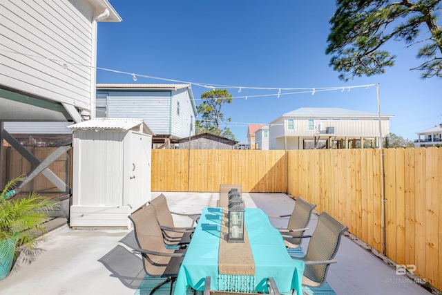 view of patio / terrace featuring a storage shed, a fenced backyard, an outbuilding, and outdoor dining space