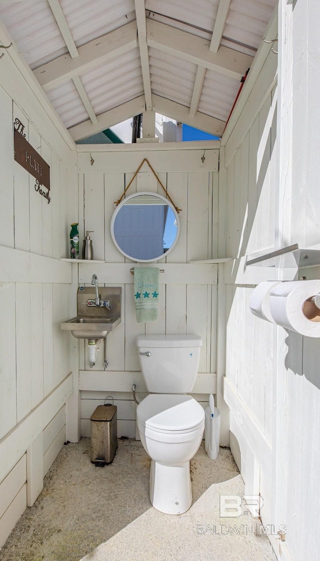 bathroom with lofted ceiling with beams, a sink, and toilet