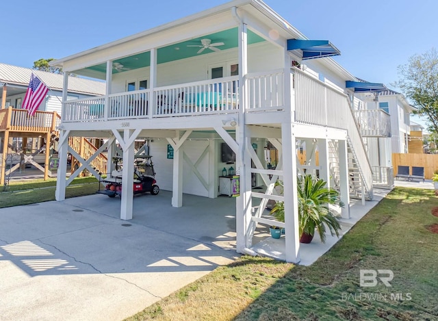 back of house with a carport, a yard, stairway, and driveway