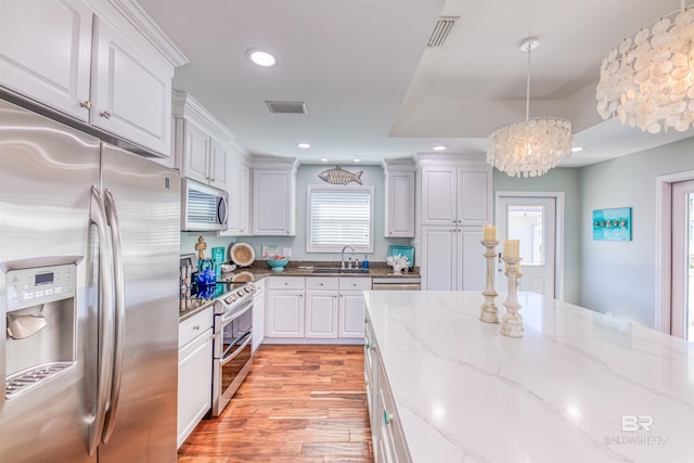 kitchen featuring stainless steel appliances, a sink, visible vents, and white cabinets