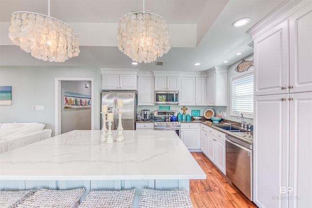 kitchen with a chandelier, stainless steel appliances, light wood-type flooring, and a sink