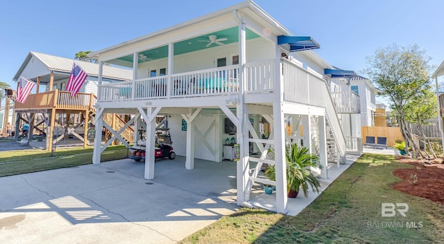 rear view of house featuring driveway, stairway, a carport, and a yard