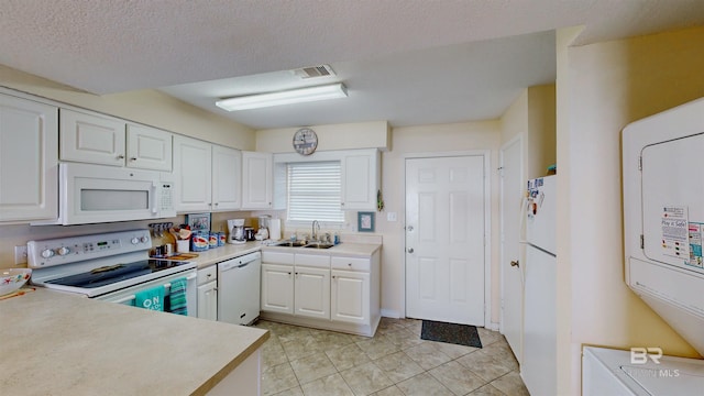 28835 Perdido Beach Blvd Unit 309, Orange Beach, AL 36561 - kitchen featuring white appliances, a sink, white cabinets, light countertops, and stacked washer / dryer
