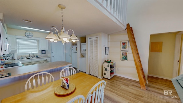 28835 Perdido Beach Blvd Unit 309, Orange Beach, AL 36561 - dining area featuring estacked washer and dryer, a chandelier, light wood-style floors, and baseboards
