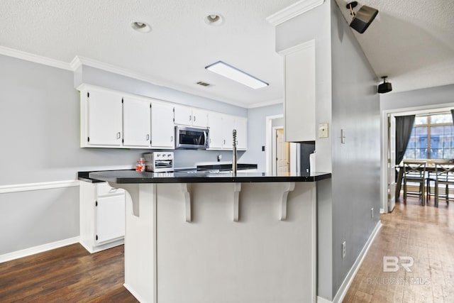 kitchen featuring kitchen peninsula, a breakfast bar, white cabinets, crown molding, and dark hardwood / wood-style floors