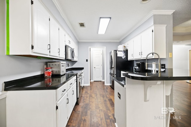 kitchen with white cabinetry, stainless steel appliances, dark wood-type flooring, kitchen peninsula, and ornamental molding