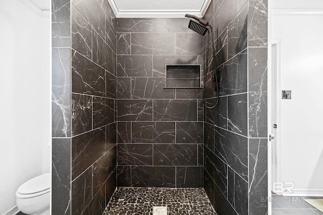 bathroom with tiled shower, toilet, and ornamental molding