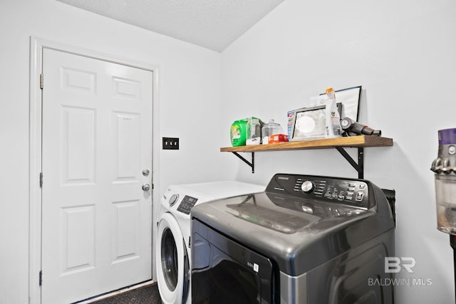 clothes washing area with independent washer and dryer and a textured ceiling