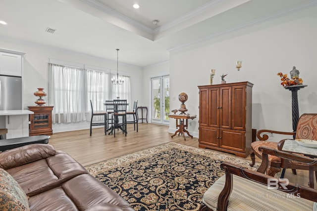 living room featuring light hardwood / wood-style floors, crown molding, and a chandelier