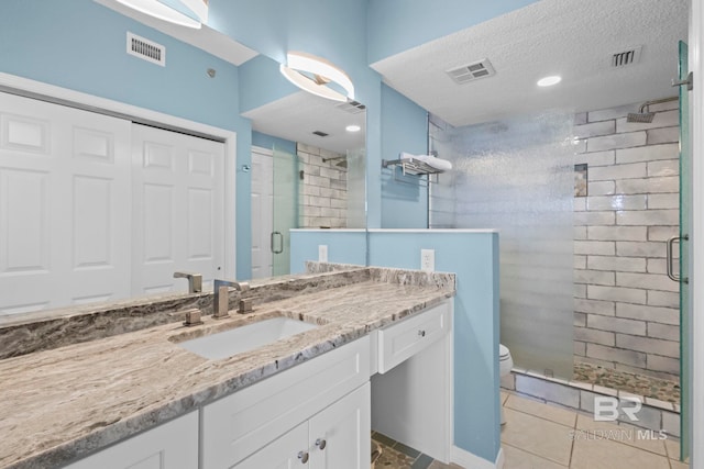 bathroom featuring a textured ceiling, toilet, a stall shower, and visible vents