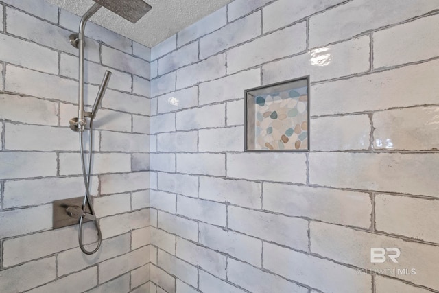 interior space with a tile shower and a textured ceiling