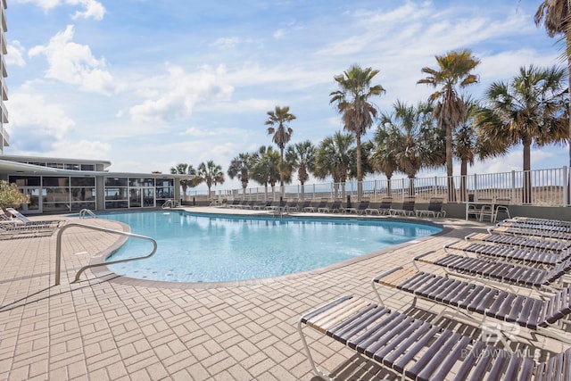 community pool with a patio area and fence