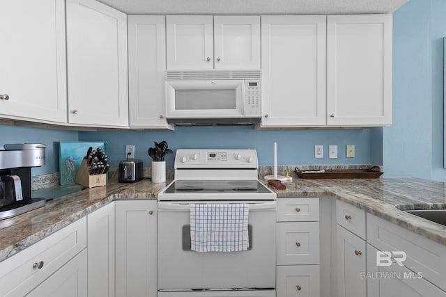 kitchen with white appliances, light stone countertops, and white cabinets