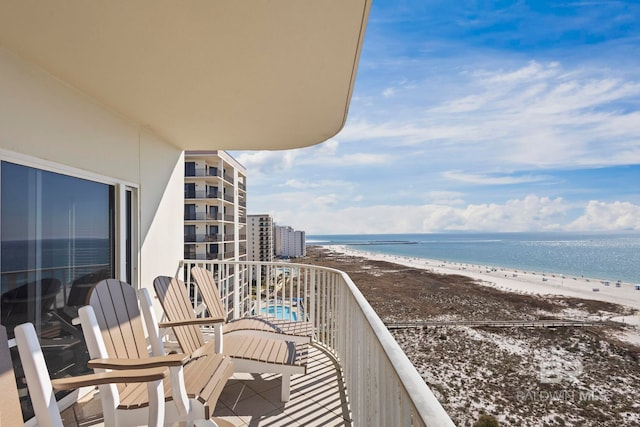 balcony featuring a view of the beach and a water view