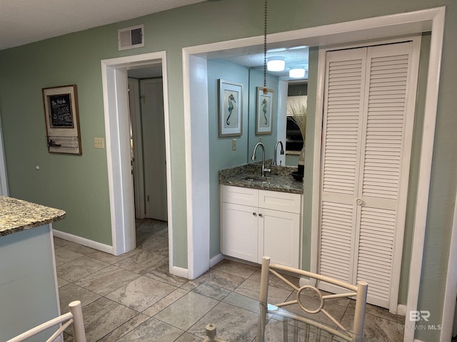 bathroom with a closet, visible vents, vanity, and baseboards