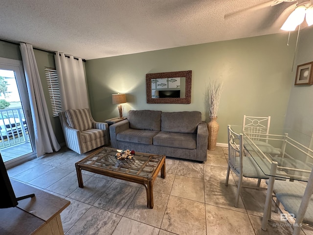 living area featuring a textured ceiling, light tile patterned floors, and baseboards