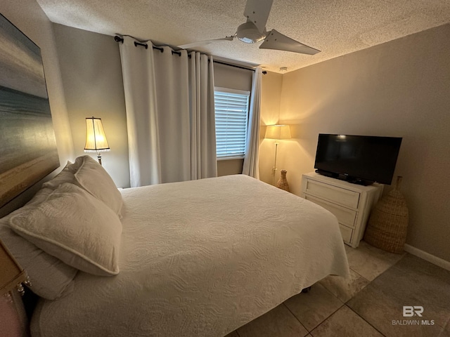 bedroom featuring light tile patterned floors, baseboards, a ceiling fan, and a textured ceiling