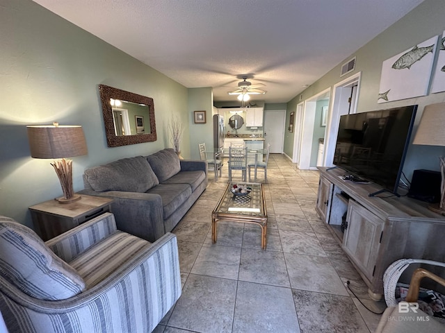 living room featuring a textured ceiling, visible vents, and a ceiling fan