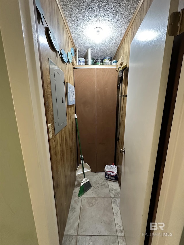 bathroom with electric panel, wooden walls, and a textured ceiling