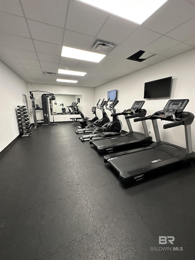 exercise room featuring a paneled ceiling, baseboards, and visible vents