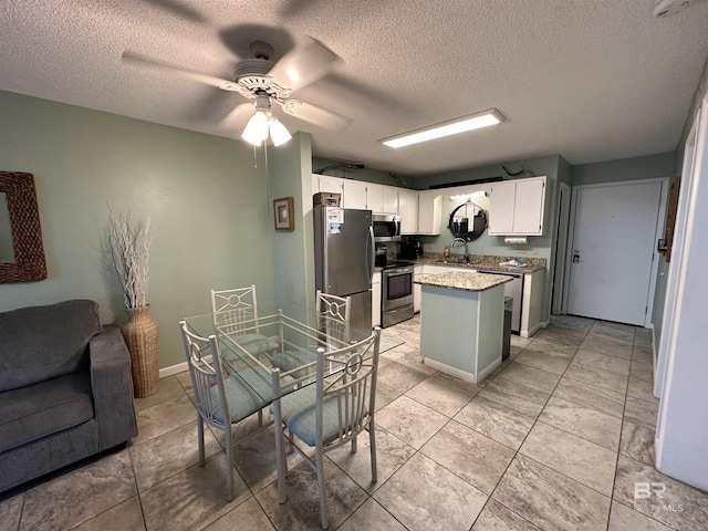 kitchen with a center island, stainless steel appliances, open floor plan, white cabinets, and a sink