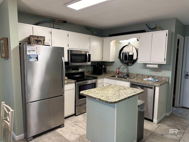 kitchen featuring appliances with stainless steel finishes, white cabinets, a sink, and light stone counters