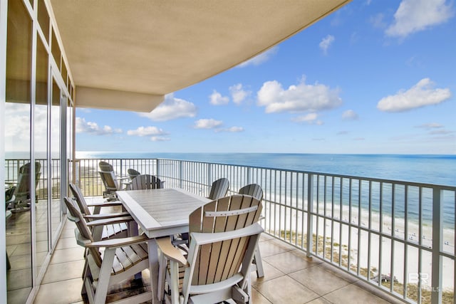 balcony with view of water and beach and outdoor dining space