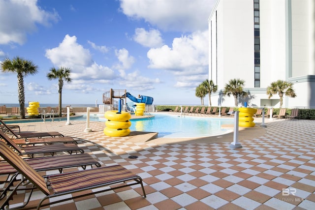 community pool with a water slide and a patio area