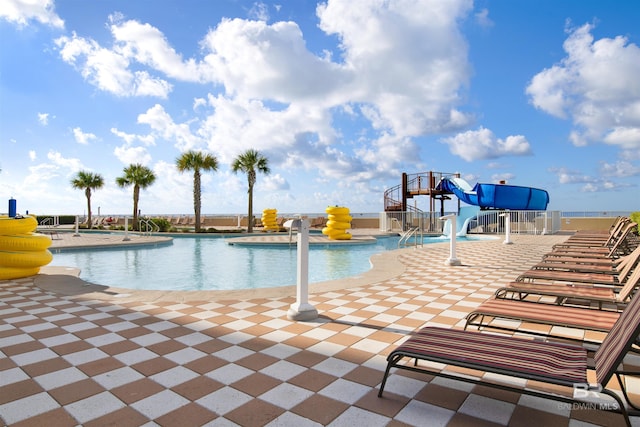community pool with a water slide and a patio