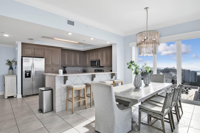dining area with crown molding, a chandelier, light tile patterned flooring, a raised ceiling, and recessed lighting
