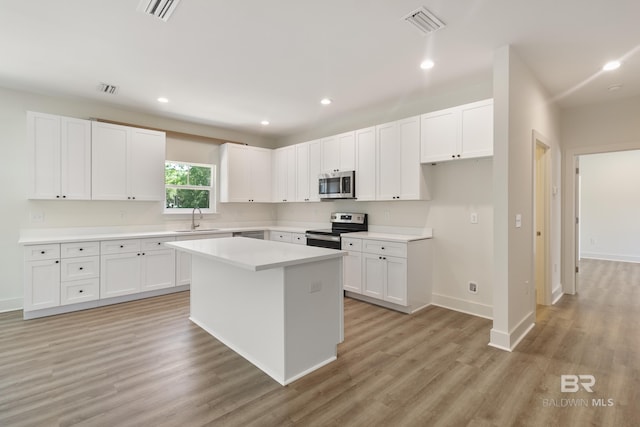9264 Brighton Ave, Elberta, AL 36530 - kitchen with stainless steel appliances, a sink, light wood-type flooring, a kitchen island, and white cabinets