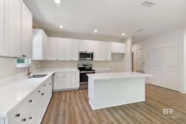 9264 Brighton Ave, Elberta, AL 36530 - kitchen with stainless steel appliances, a sink, light wood-type flooring, a kitchen island, and white cabinetry