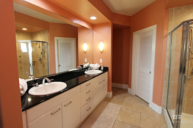 bathroom with a shower with shower door, tile flooring, and dual vanity